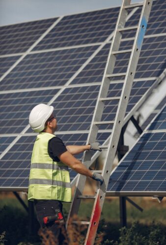 Man in a white helmet near a solar panel Engineer in a white helmet. Man near solar panel. Worker with a ladder